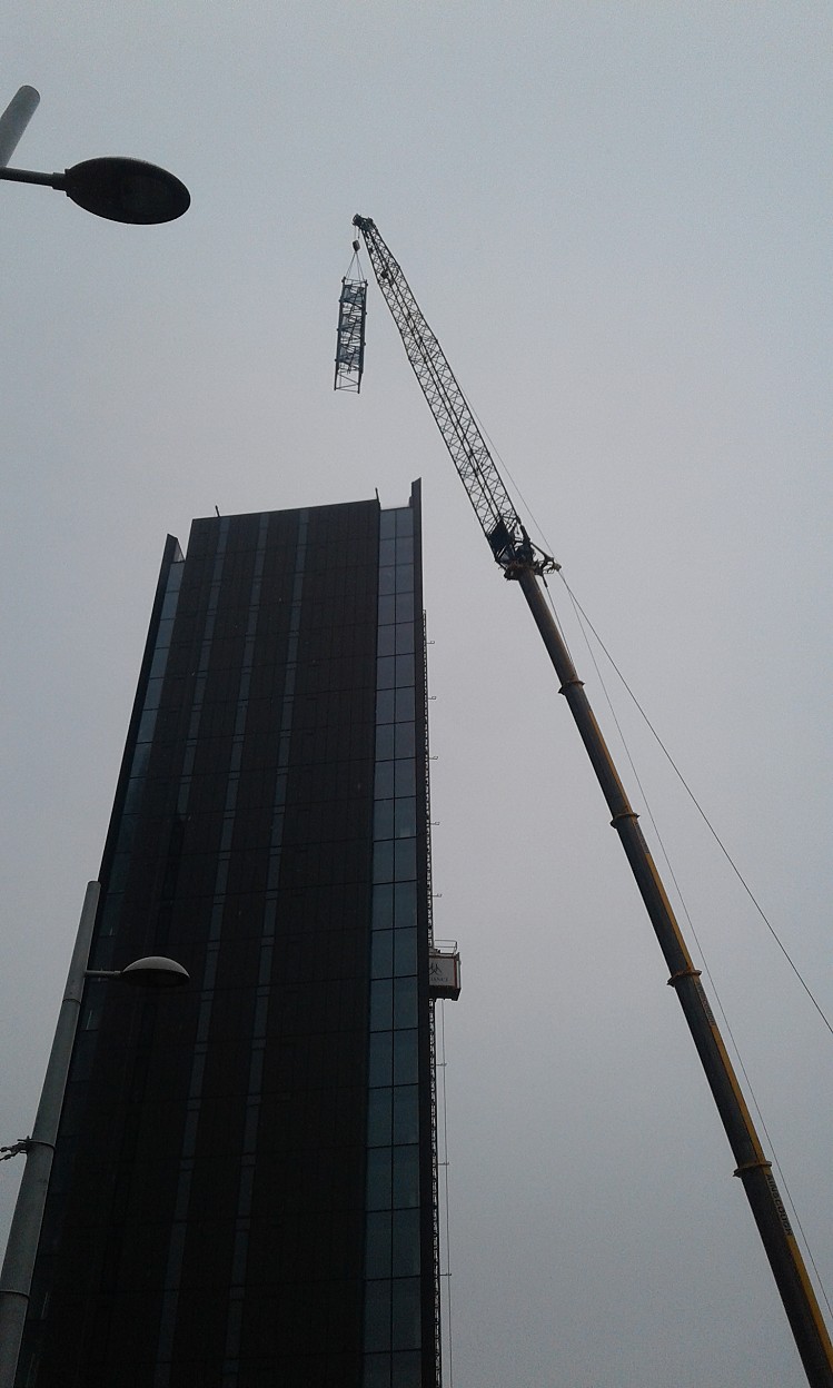 The enormous mobile crane removes a piece of the tower crane